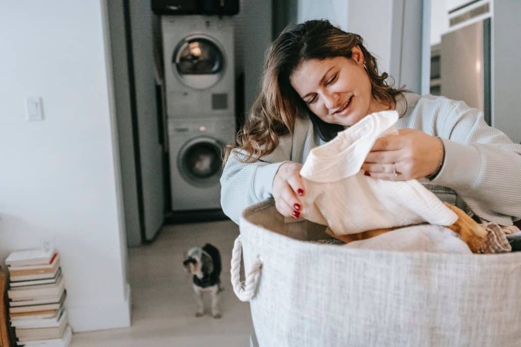 Positive woman with clean clothes speaking on smartphone - how to sort your laundry