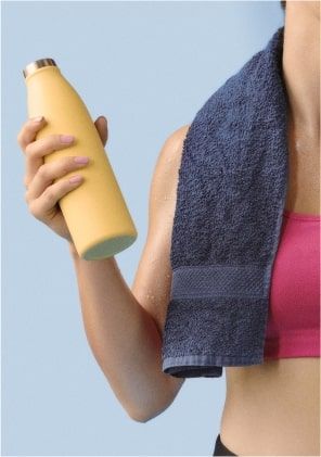 A sportswoman holds her water bottle with her towel over her shoulder